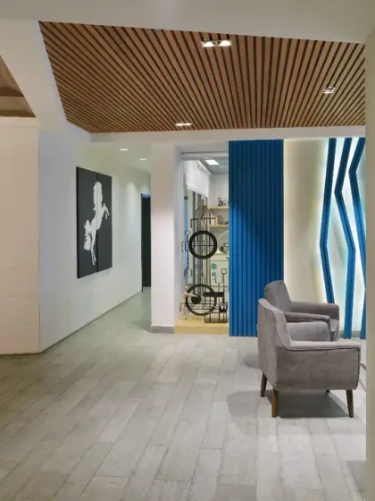 By removing unnecessary partitions in the Grey Apartment, the living room now flows effortlessly into adjacent areas. A geometric feature wall and slatted wood ceiling guide the eye, creating a sense of openness and volume.