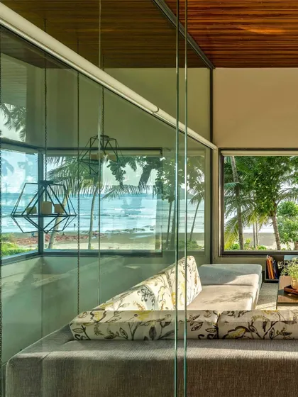 Another view of the living space at the Cove, where the glass corner offers a panoramic experience of the sea and sky. The furniture is kept low and neutral to ensure nothing obstructs the connection to the natural world outside.