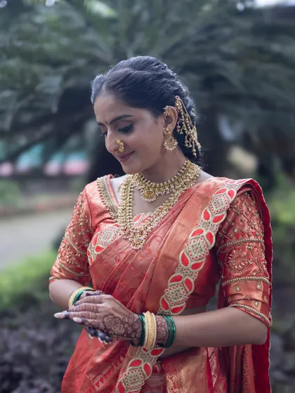 The elegance of a traditional orange Nauvari saree, complete with green bangles and gold jewellery. A timeless look for any Maharashtrian bride.