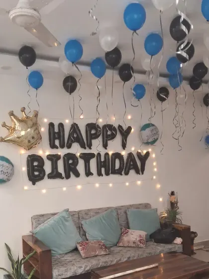 A simple and elegant birthday room setup with blue, black, and white balloons. The 'Happy Birthday' foil letters and a crown foil balloon complete the look.