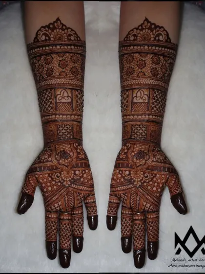 A classic and elegant full bridal mehendi with traditional motifs and symmetrical patterns from the fingertips to the elbows.
