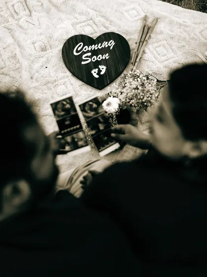 An over-the-shoulder shot of the couple looking at their sonogram pictures together during a picnic. It's an intimate and shared moment of discovery.
