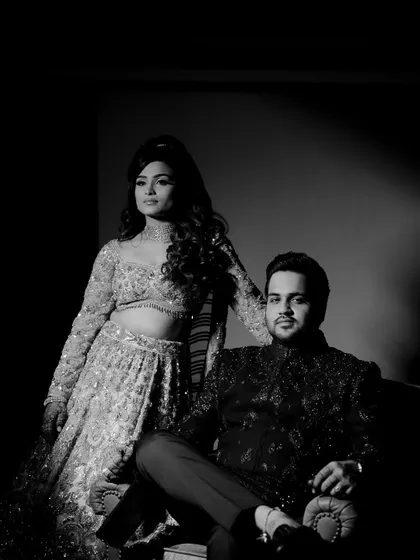 A powerful, high-contrast black and white portrait of the couple on their Sangeet night. The dramatic lighting captures their regal presence and the glamour of the event.