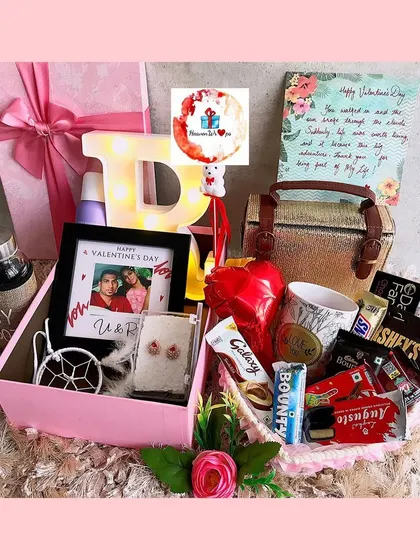 A lavish pink-themed birthday box filled with a variety of gifts, including a handbag, a personalized photo frame, a light-up initial, and an assortment of chocolates and self-care items.