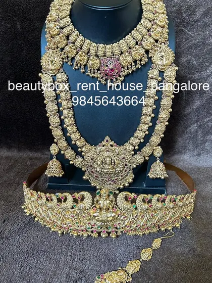 An antique-finish bridal set with a choker, a layered haaram, and a matching peacock-motif vaddanam.