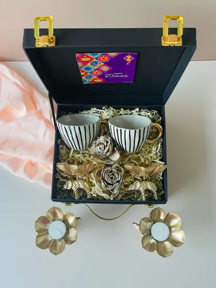 An overhead shot of our popular black suitcase hamper, showcasing the arrangement of the striped cups and golden decor items nestled in protective shred.