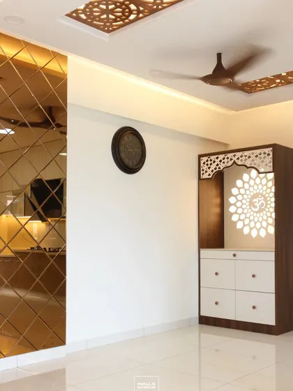 This pooja unit is placed in a living area, complemented by a bronze mirror wall and CNC-cut ceiling panel. The design shows how we integrate spiritual spaces into the overall home decor.