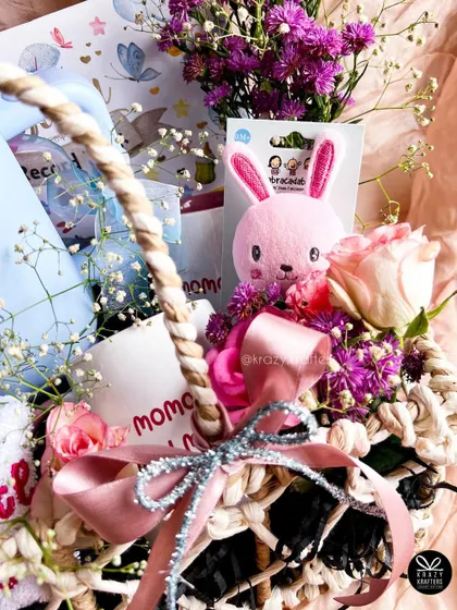 A close-up on the details of the baby shower basket, featuring a cute pink bunny toy, fresh flowers, and a sparkling ribbon.