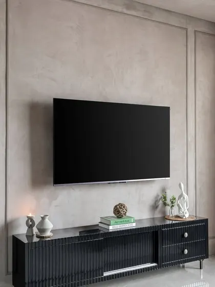The TV unit in 'Maison-De-Confort'. The textured lime-wash wall and minimalist black console create a sophisticated, modern look.