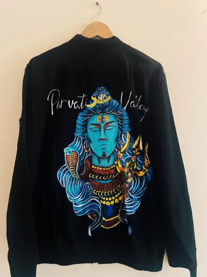This black bomber jacket features a powerful hand-painted portrait of Lord Shiva. I focused on creating vibrant colors and intricate details in his expression, the Trishula, and the serpent, making it a statement piece of spiritual art.