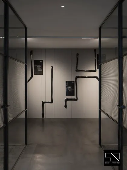An art-filled corridor with dramatic black sculptural pieces mounted on the wall. This transforms a simple passageway into a gallery-like experience, reflecting the company's creative and modern identity.