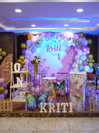 A beautiful butterfly setup with a purple and gold color scheme, complete with themed pedestals and a light-up 'ONE' sign.