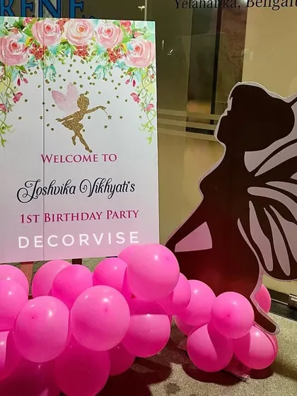 A close-up of the personalized welcome sign for Joshvika's first birthday. The sign features a floral fairy design and is paired with a silhouette cutout, setting the enchanting tone for the event.