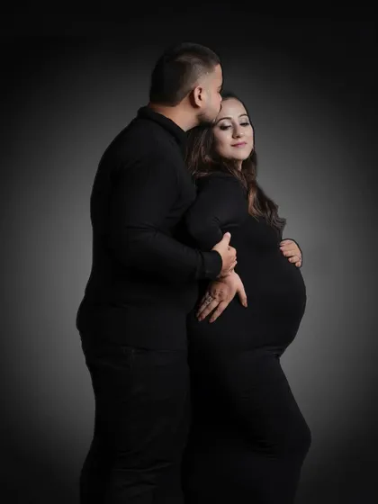 A classic and powerful portrait against a dark backdrop. The focus is entirely on the couple's embrace and the beautiful silhouette of the baby bump.