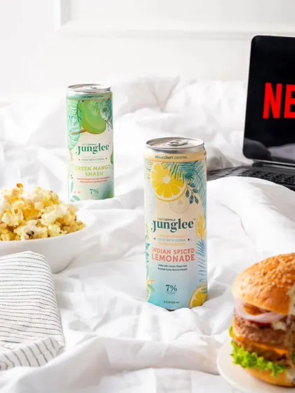A lifestyle shot for Junglee canned cocktails, creating a "Netflix and chill" scene. This places the product in a relatable context, associating it with relaxation and casual fun.