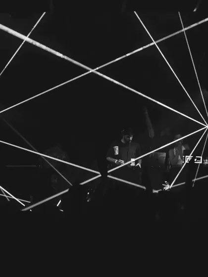A black and white shot capturing the geometric laser patterns during a set. The light show is as much a part of the performance as the music itself.