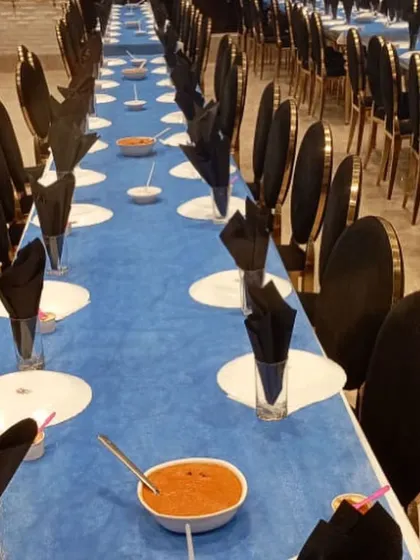 A long view of our formal dining setup. The striking blue and black theme, with neatly folded napkins and pre-set dishes, shows our ability to execute a sophisticated and large-scale seated dinner service.