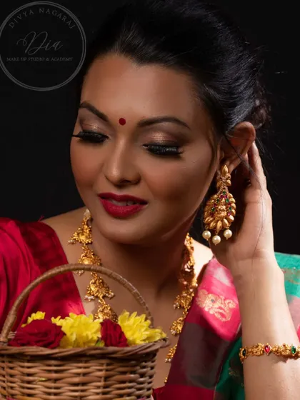 A festive and warm look from a photoshoot. The makeup features golden, shimmery eyes and a classic red lip, perfect for celebrating special occasions. The model's soft expression adds to the gentle, festive glow.