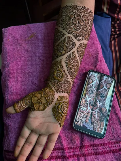 The palm-side view of this intricate engagement mehendi. The design features a beautiful flower on the back of the hand.