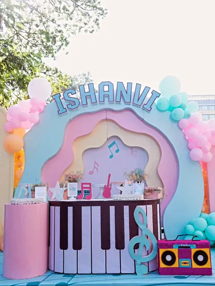 The main stage for Ishanvi's fourth birthday featured a custom-built backdrop with organic, wavy layers in pastel colors and a piano-themed dessert bar, creating a perfect photo opportunity.