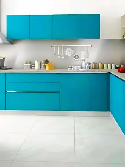 A vibrant turquoise blue gives this L-shaped kitchen a cheerful and energetic vibe. The handleless, flat-panel cabinets create a super-sleek look, while the white walls and floor keep the space feeling bright and open.