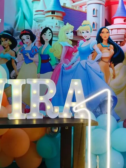 A close-up of the princess-themed cake table, with the birthday girl's name in light-up letters surrounded by Disney princess characters.