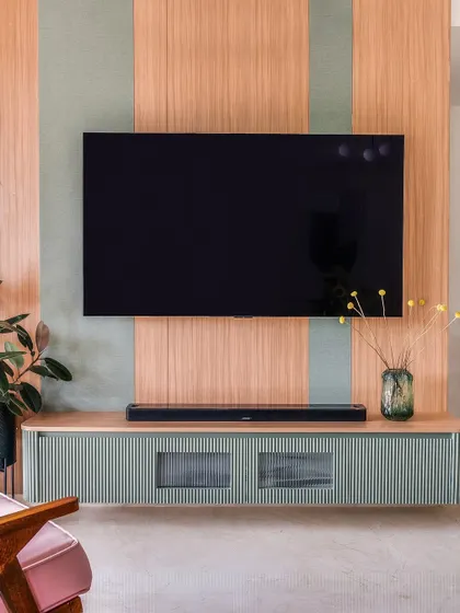 This floating TV unit combines a mint green fluted console with a wood-paneled backdrop, offering a sleek and modern storage solution.