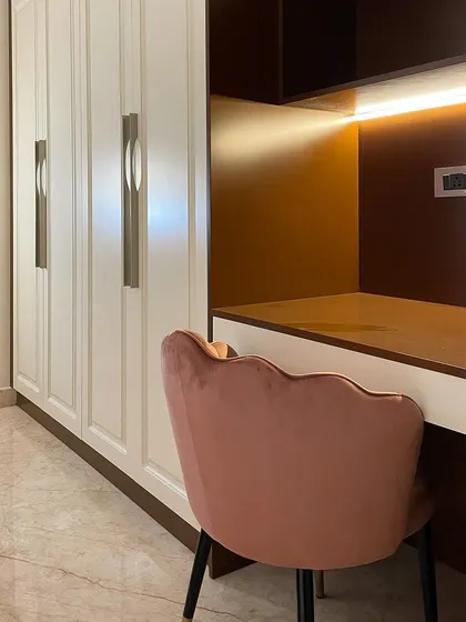 We integrated a compact study and work-from-home area into this bedroom's wardrobe unit. The dusty rose chair complements the room's color scheme and adds a touch of elegance to the functional space.