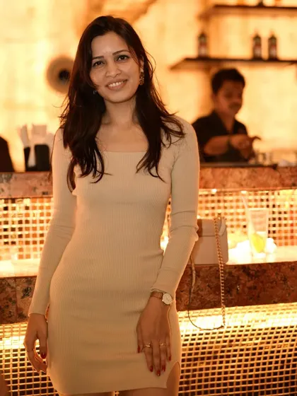 A guest in a chic beige dress, posing by the bar at Pangeo.