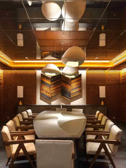 A full view of the basement dining room, showcasing the custom-designed table, chairs by Mahendra Doshi, and lights by Design ni Dukaan. The mirrored ceiling reflects the intricate details, enhancing the sense of enclosure and luxury.