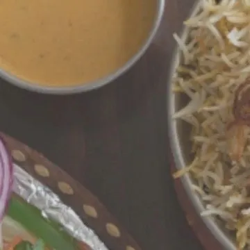 A close-up of our delicious Mughlai biryani, served with raita. Our chefs use authentic recipes and the finest ingredients to create a memorable meal.
