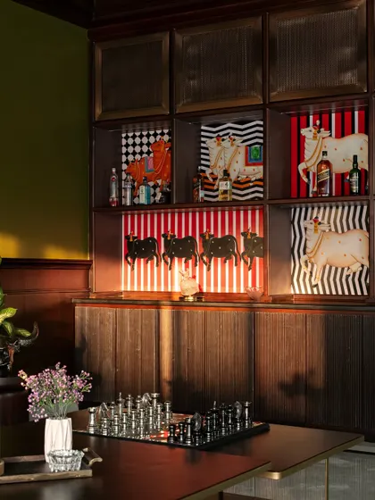Another angle of the bar area, showing the interplay of light and shadow on the fluted wood and the vibrant artwork. Every detail, from the lighting to the object placement, is carefully considered.