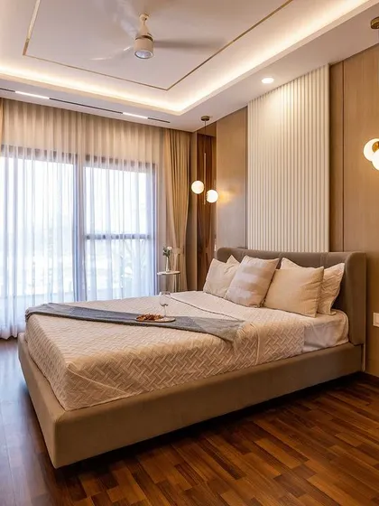 A wide view of a bedroom with rich wood-paneled walls and flooring. The large window with sheer curtains ensures the room is filled with soft, natural light.