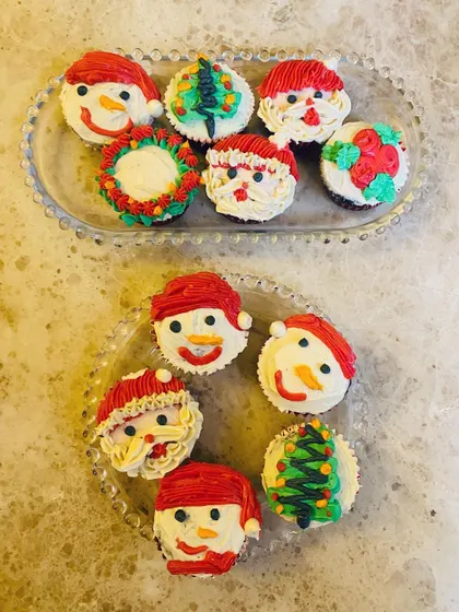 A platter of my festive Christmas cupcakes, featuring cute snowmen, Santas, and Christmas trees. They are a joyful treat for holiday parties.