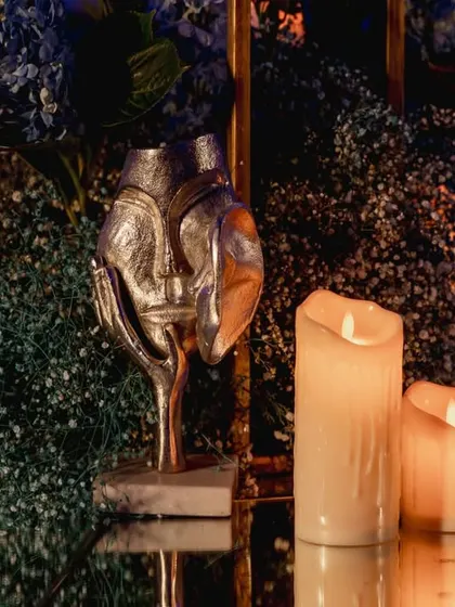 A unique silver decor piece on a mirrored table, reflecting the candlelight. These artistic details add a layer of sophistication to the overall design.