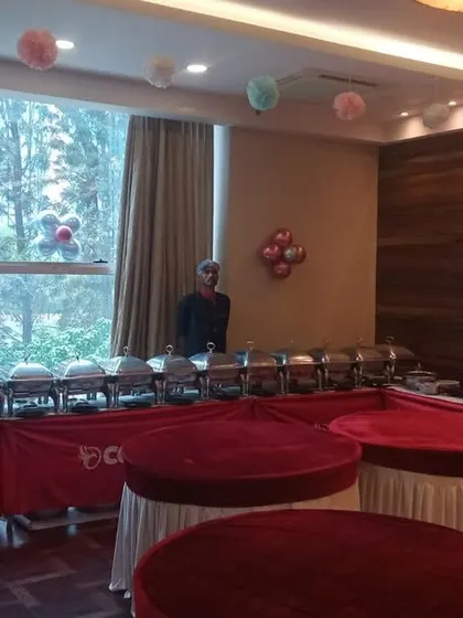 An elegant buffet arrangement for a birthday party at Mantri Glades, with round tables for desserts and a main course line by the window.