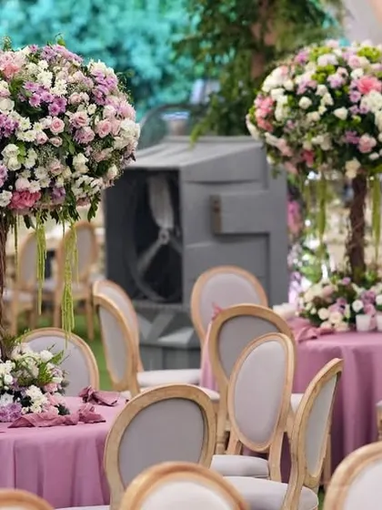 Tall, tree-like centerpieces with large bouquets of pink, purple, and white flowers add height and drama to the reception tables.