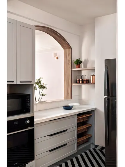 The "after" shot of a kitchen transformation, showing the finished space with sleek grey cabinets, built-in appliances, and a striped rug.