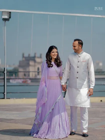 A full-length shot of the couple during their outdoor engagement session. The bride's lavender lehenga looks stunning against the bright blue sky.