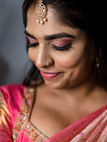 A close up portrait of a bride with a playful, happy expression. The focus on her face captures her excitement and the beautiful details of her makeup and jewelry.