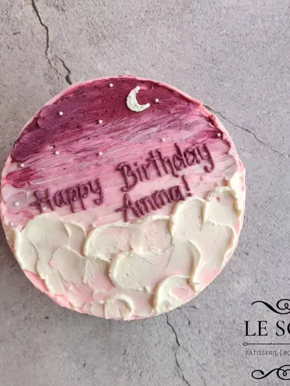 A dreamy, minimalist cake with a painted sky effect. This half-kg Ferrero Crunch cake features a pink and purple sky with a crescent moon, all created with buttercream.