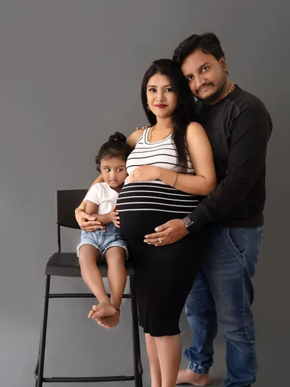 A lovely family portrait with their daughter seated on a chair, creating a fun and engaging composition.