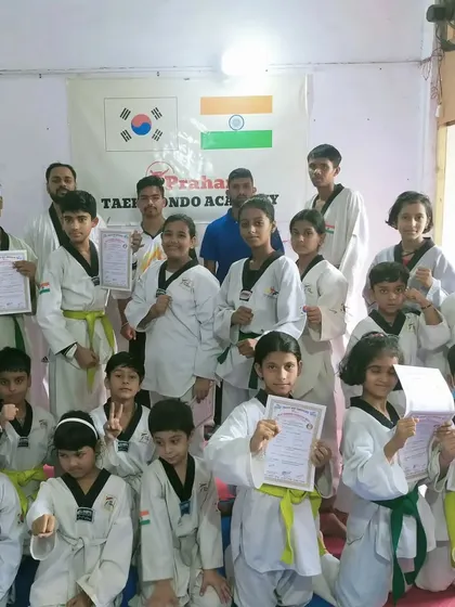 A group of our students, from yellow to green belts, proudly holding their promotion certificates.