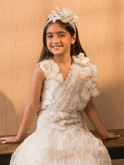 This handcrafted white lehenga is adorned with delicate floral appliqués and pearl embellishments for a soft, romantic look.