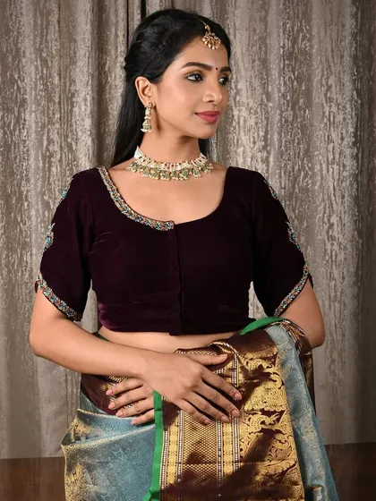 A model pairs a deep purple velvet blouse with a classic kundan and pearl choker. The rich texture of the velvet makes the jewellery pop.