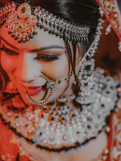 A stunning close-up portrait of the bride, with dramatic lighting highlighting her beautiful makeup and jewelry.