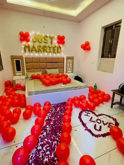 A "Just Married" first-night room decoration. The room is filled with red balloons, with a path of rose petals leading to the bed and an "I LOVE U" message.