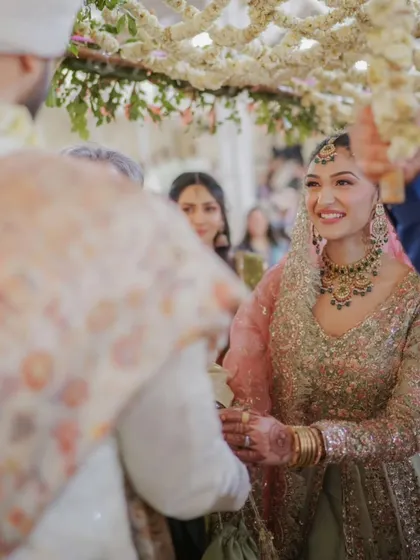 A close-up shot of the bride's happy expression as she sees her groom for the first time. The 'phoolon ki chadar' beautifully frames this emotional moment.