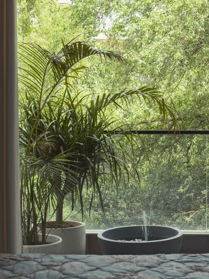 A close-up of the balcony view from the bedroom, where a small water feature and potted palms create a personal oasis.