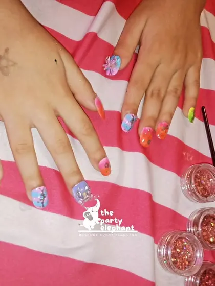 A finished set of mermaid-themed nail art, complete with glitter and tiny gems. It's these small, themed details that make the experience so special for the kids.
